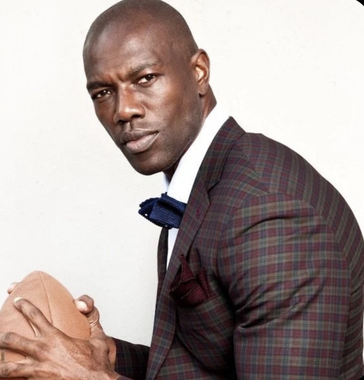 Terrell Owens in a tailored plaid suit holding a football